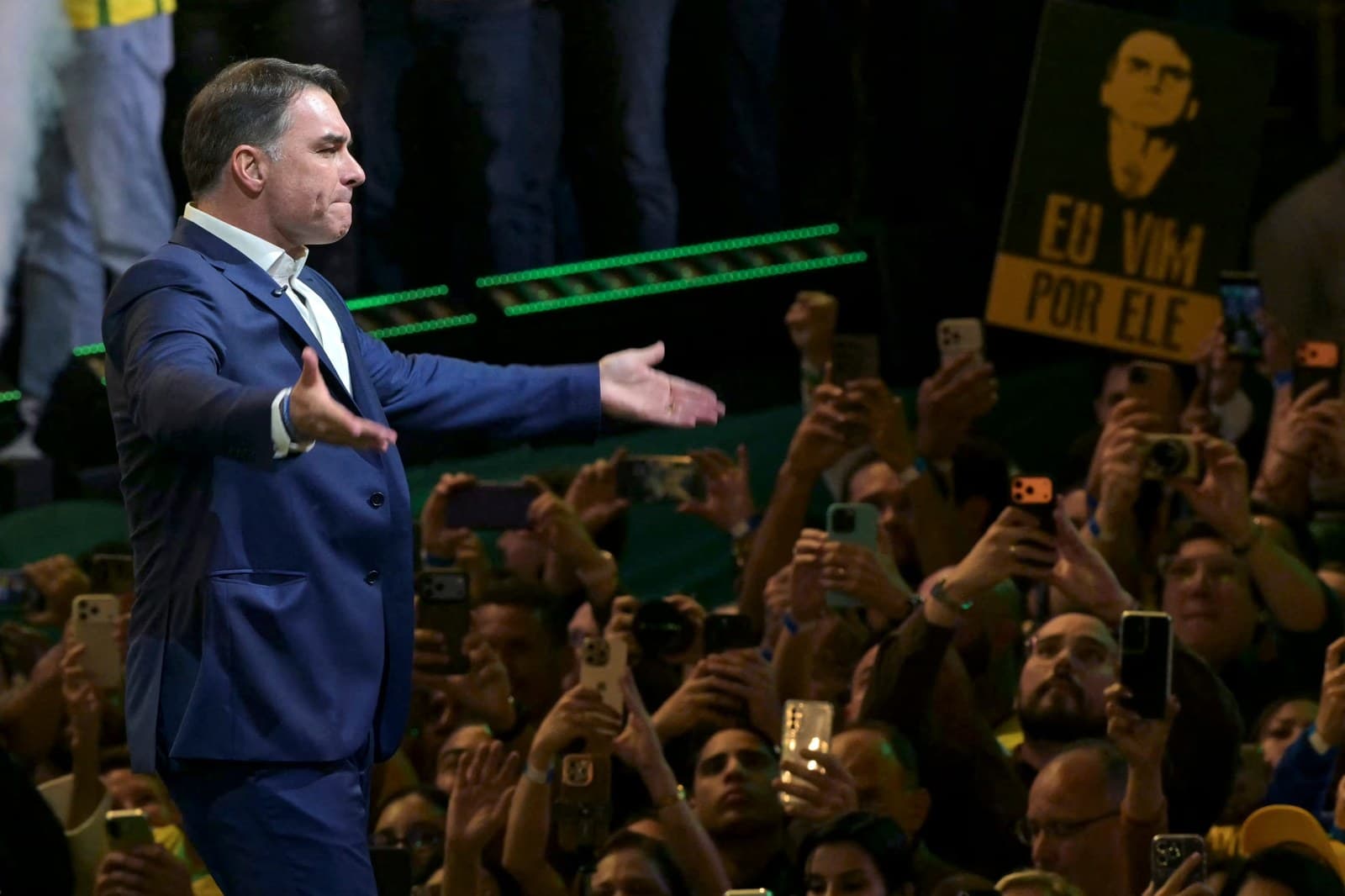 Flávio Bolsonaro saluda con los brazos abiertos a sus seguidores en un acto de campaña