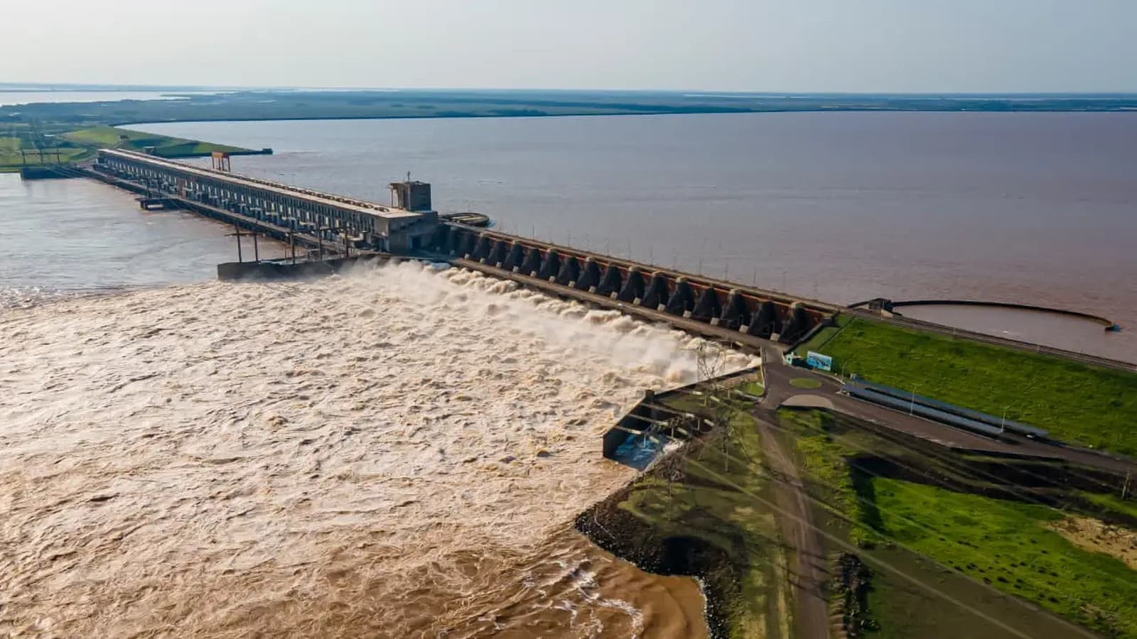 Vista aérea de una represa sobre el río Paraná con las compuertas del vertedero abiertas