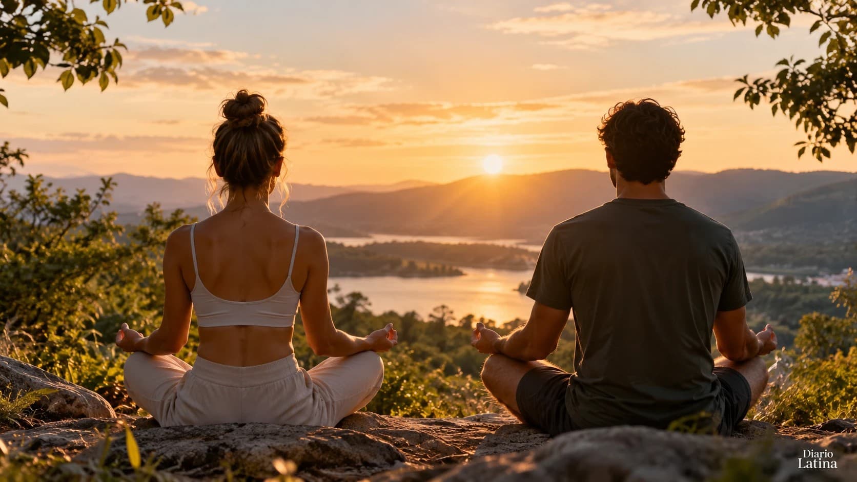 Una pareja medita sentada sobre una roca frente a un lago al atardecer