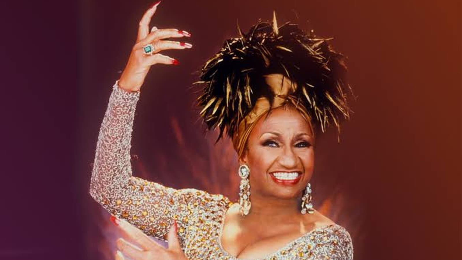 Celia Cruz sonríe con un tocado de plumas y un vestido brillante