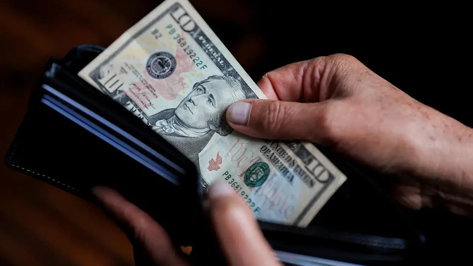 Una persona saca un billete de 10 dólares de su billetera