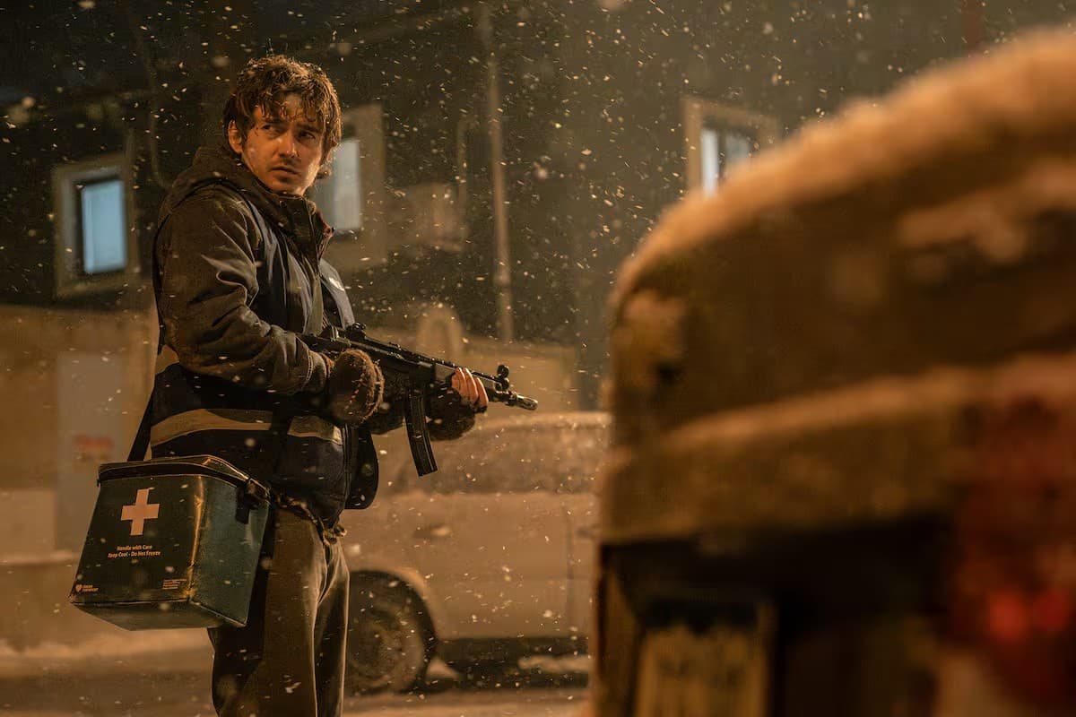 Una escena de la película Resident Evil: un hombre armado y con un maletín médico, bajo la nieve